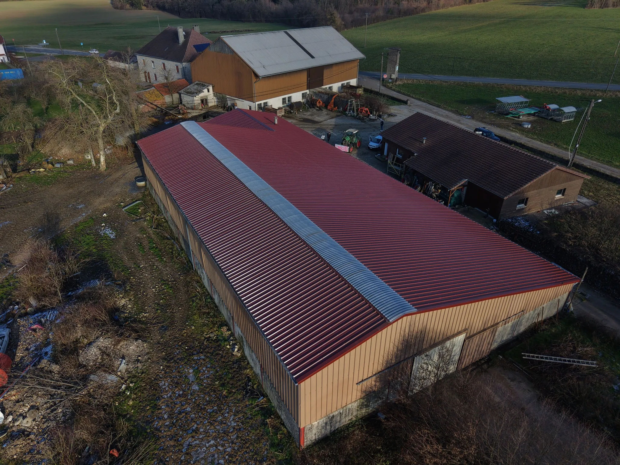 Vue drone : toiture bac acier rouge sur bâtiment agricole